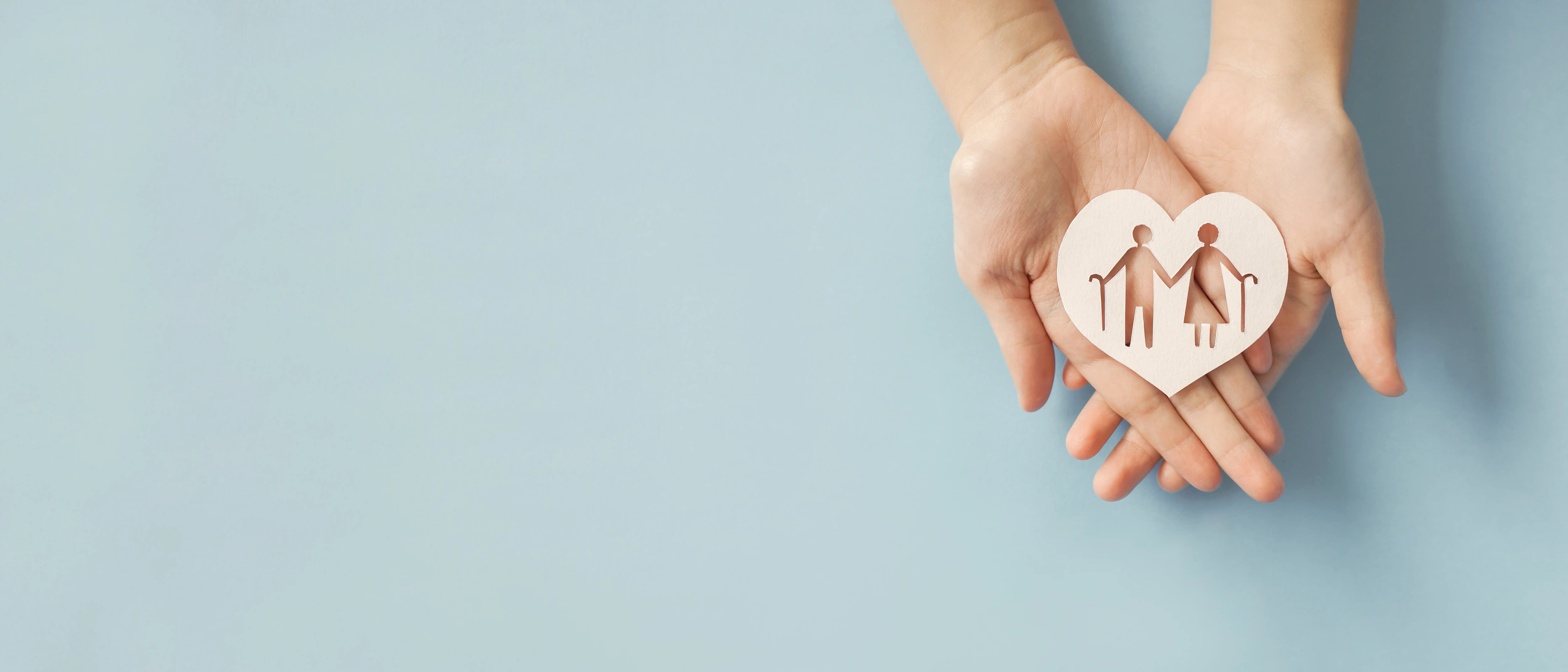 photo of hand holding heart shaped paper with old couple cutout